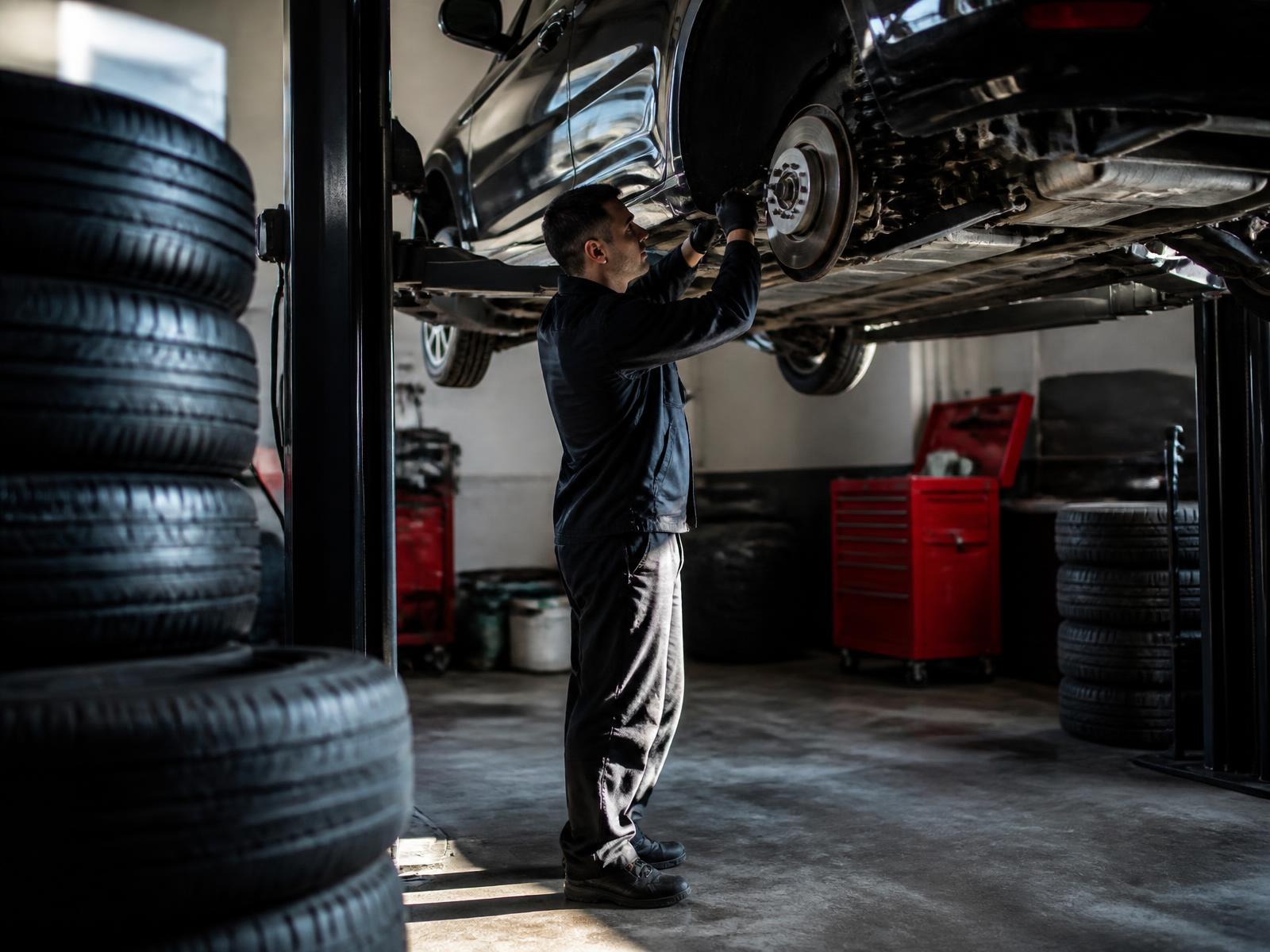 Technician servicing a vehicle on a lift at Nonstop Tires & Service in Chula Vista